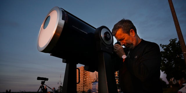 قام روبرت بورغيس ، رئيس علماء الفلك في جنوب مين ، بإعداد تلسكوب مزود بمرشحات شمسية لمشاهدة كسوف جزئي من الحفلة الشرقية في بورتلاند يوم الخميس ، 10 يونيو ، 2021.