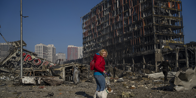 إيرينا زوبشينكو تمشي مع كلبها ماكس وسط الدمار الناجم عن قصف أحد مراكز التسوق في كييف بأوكرانيا يوم الاثنين.
