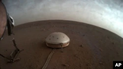 في هذه الصورة غير المؤرخة التي أتاحتها وكالة ناسا يوم الخميس 22 يوليو 2021 ، تنجرف السحب فوق مقياس الزلازل SEIS المغطى بالقبة لمركبة الإنزال InSight على سطح المريخ.