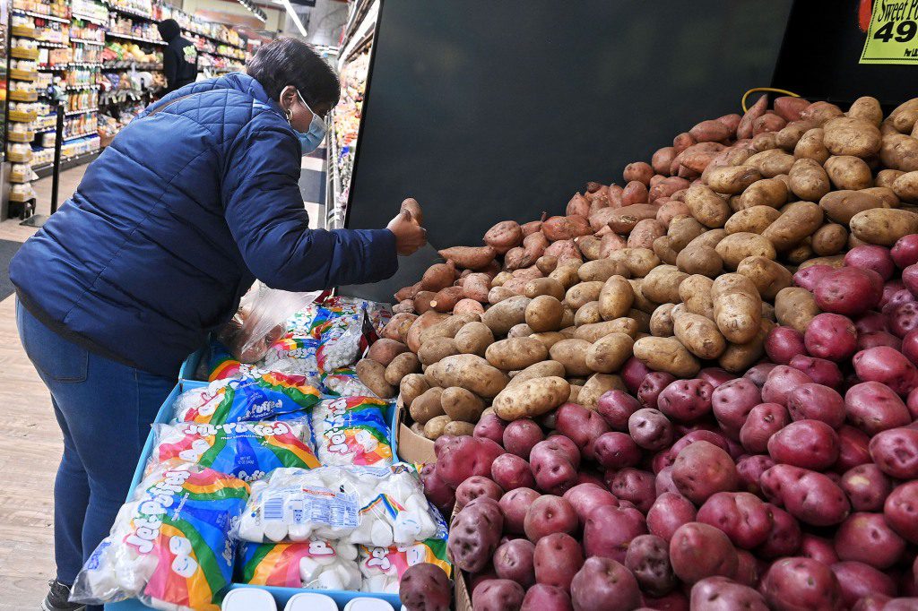 امرأة توزع البطاطس في محل بقالة.